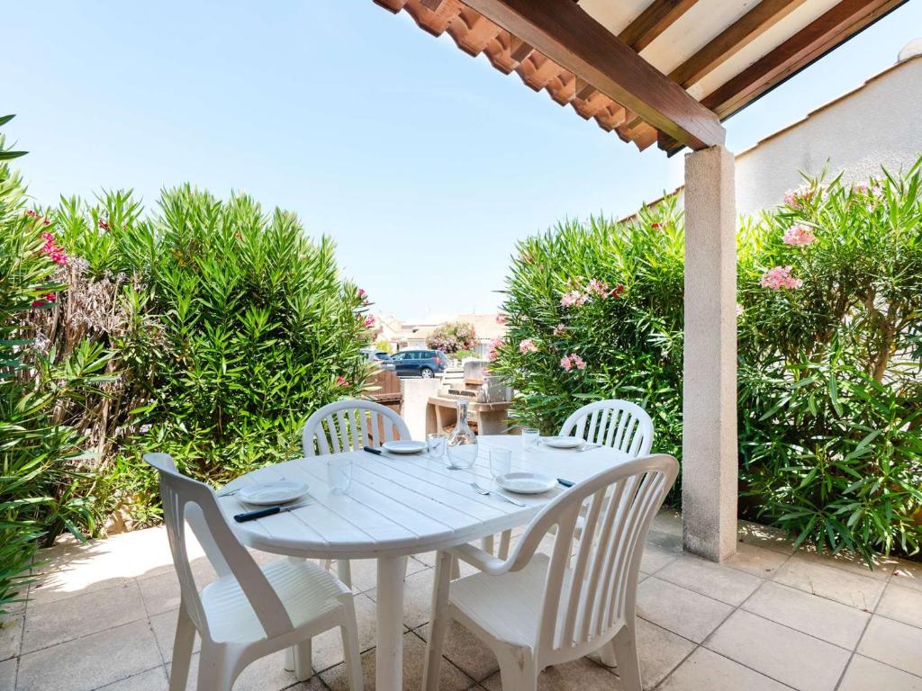 une table blanche et des chaises sur une terrasse dans l'établissement Pavillon studio mezzanine climatisé proche plage et lagune à Gruissan - FR-1-409-273, à Gruissan