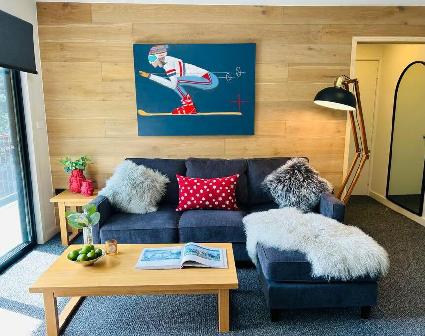 a living room with a blue couch and a table at First Tracks Studio in Thredbo