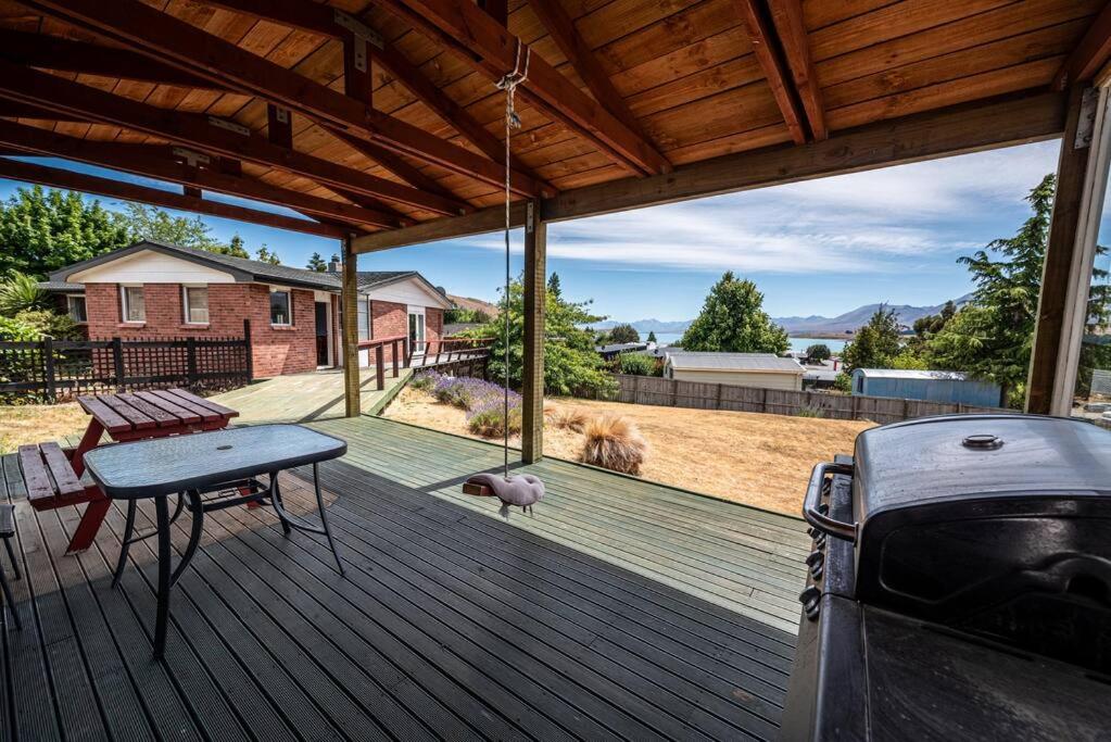 a wooden deck with a picnic table and a dog at River Retreat - Lake Tekapo in Lake Tekapo