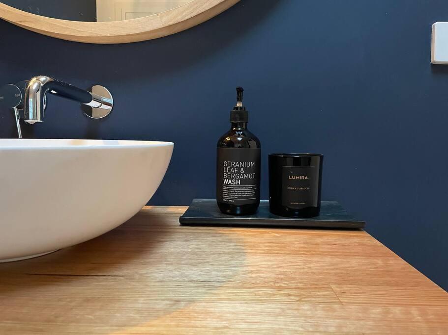 a bathroom with a sink and a bottle on a counter at The Small House - Mid century gem in wine county's Healesville in Healesville