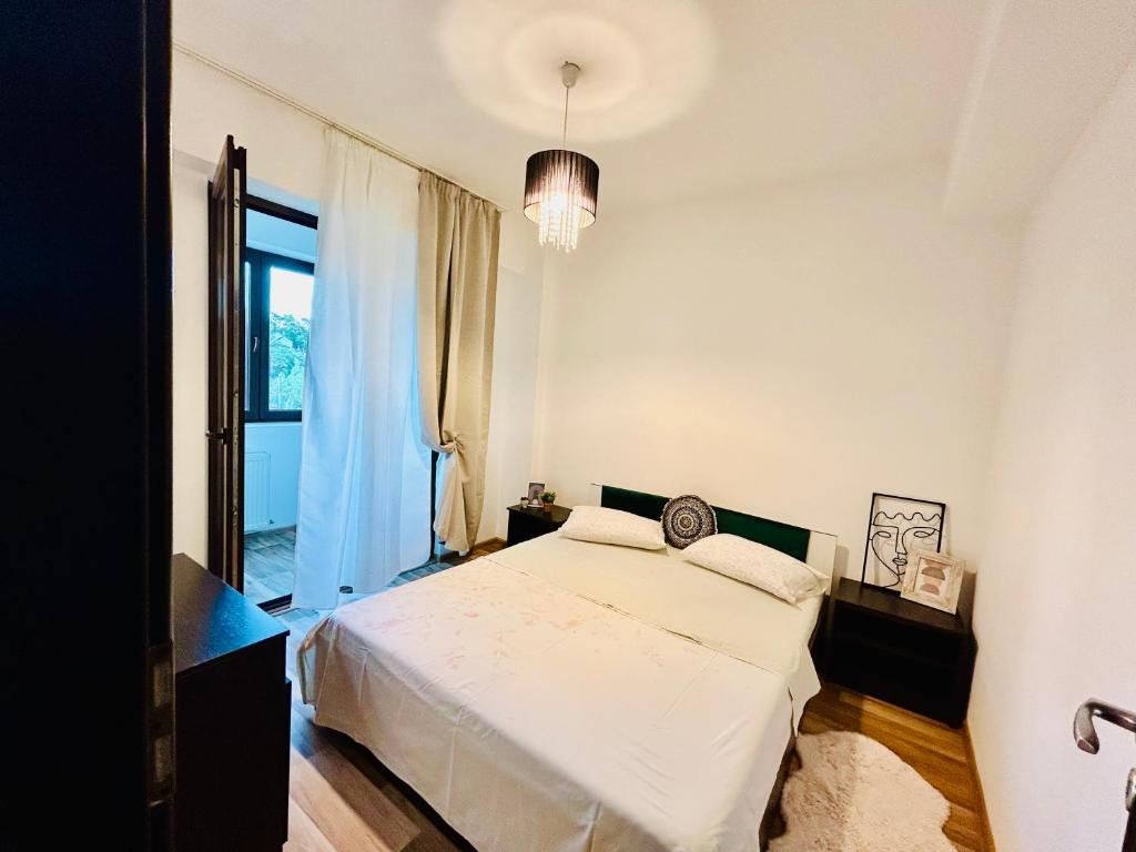 a white bedroom with a bed and a window at Ultracentral Palas in Iaşi