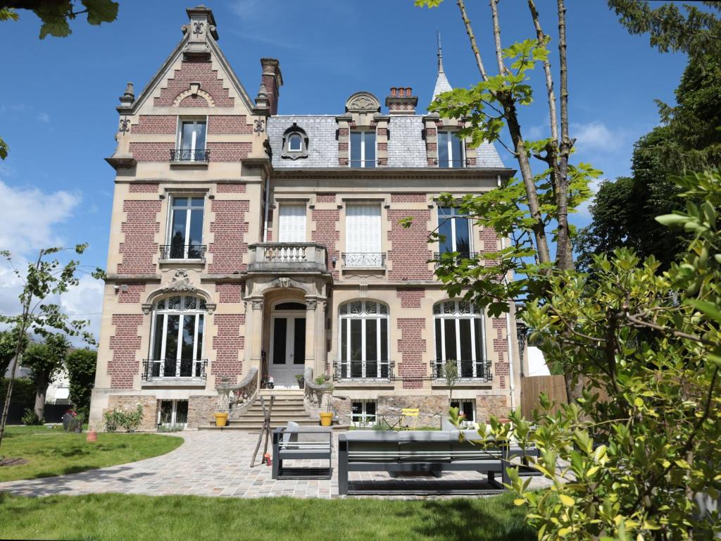 un vieux bâtiment en briques avec des bancs devant lui dans l'établissement Villa Stella, à Compiègne