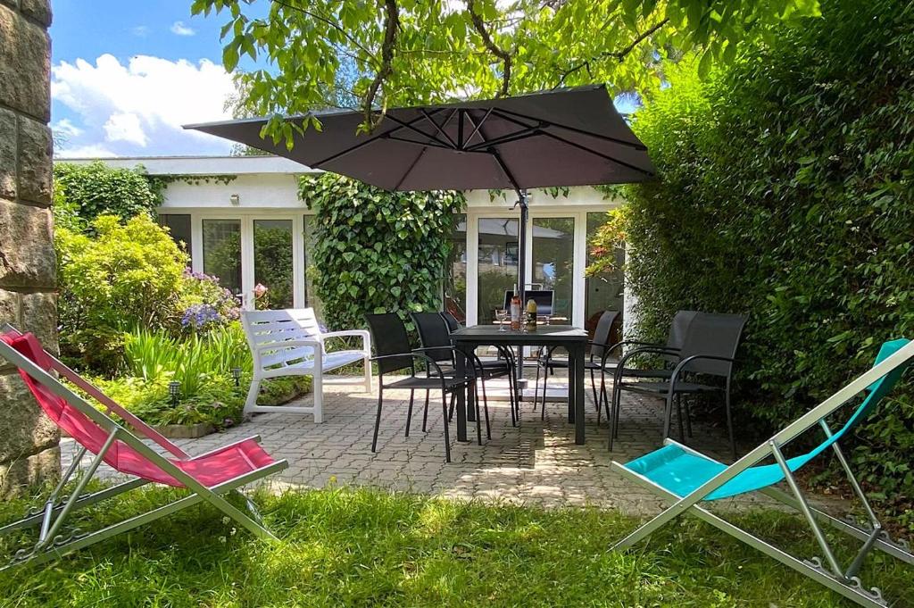 un patio avec une table, des chaises et un parasol dans l'établissement La Villa FranceYann, à Carnac