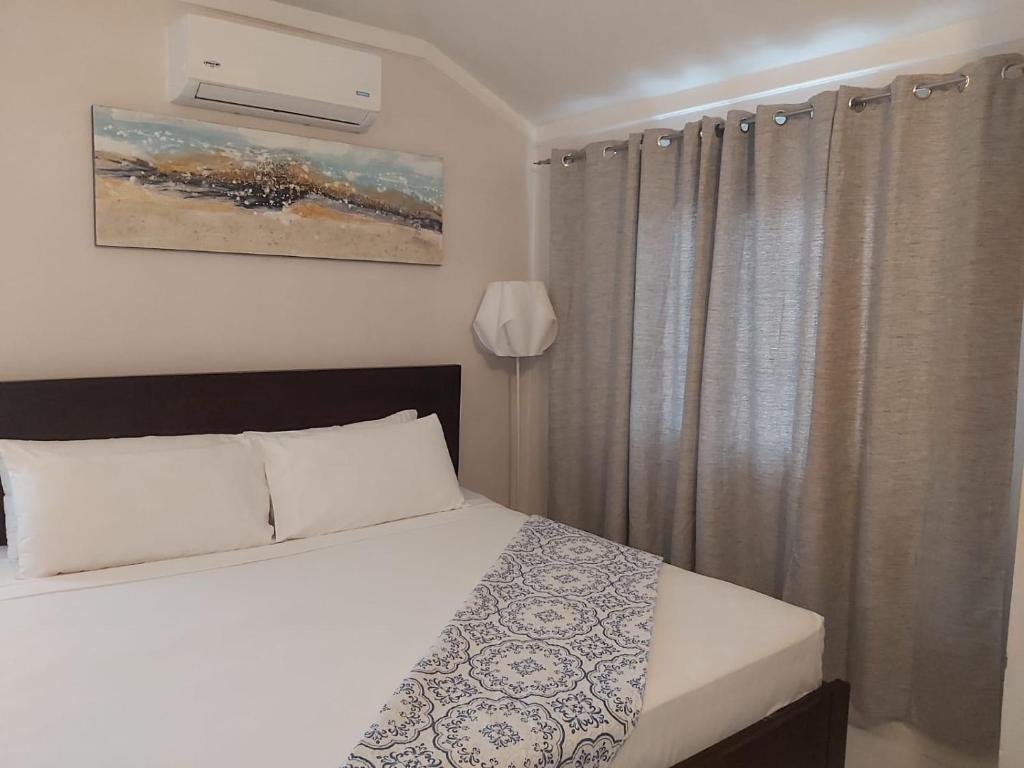 una camera da letto con un letto e una finestra con tende di The Island Flat Villa - Near Airport & Beach a Montego Bay