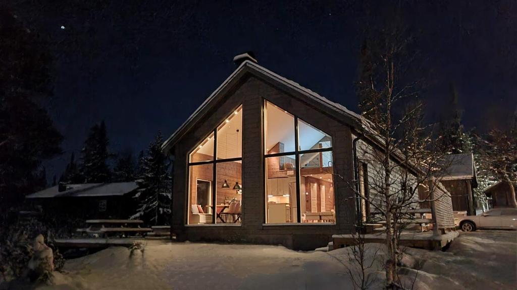 a small house with large glass windows at night at Fjellyx i funäs med relax&bastu, badtunna, 13 bädd in Funäsdalen