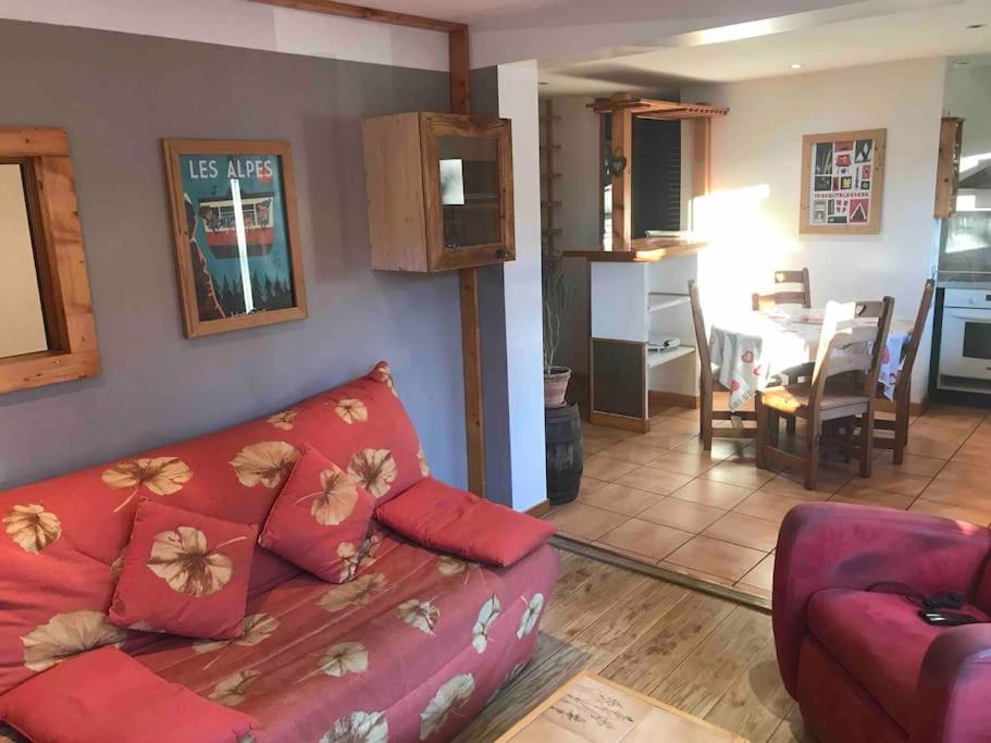 un salon avec un canapé rouge et une cuisine dans l'établissement Appartement 50m2 proche du centre Praz sur arly, à Praz-sur-Arly