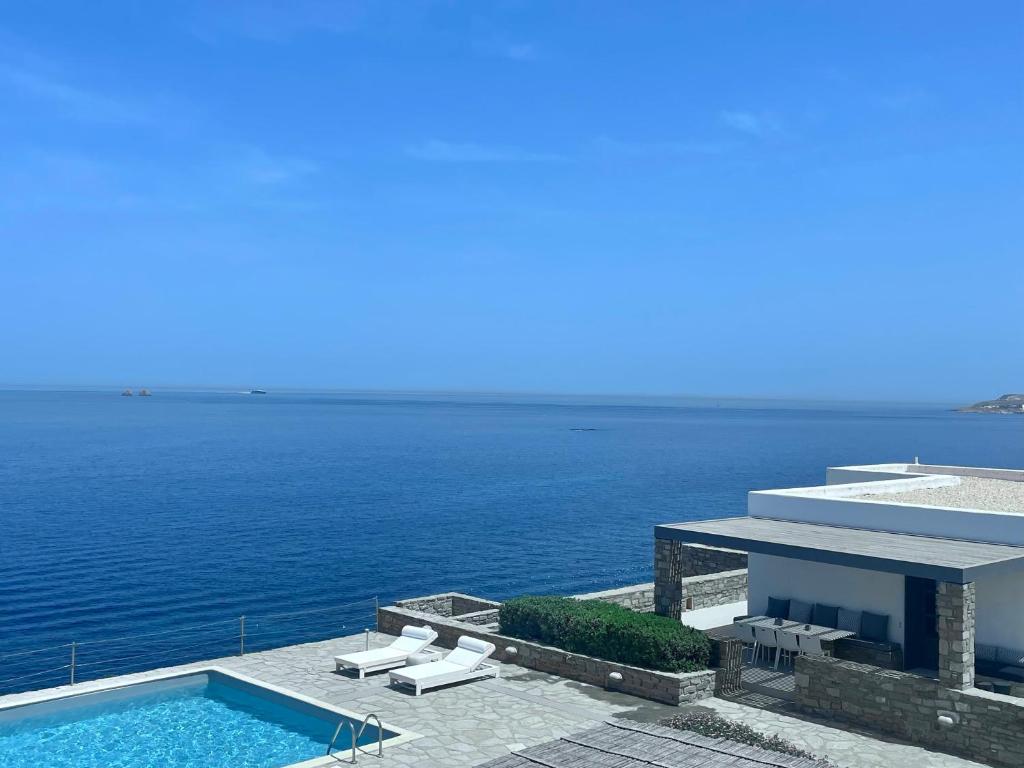 a house with a swimming pool next to the ocean at Ocean Villa Paros in Sarakíniko