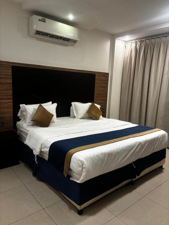 a bedroom with a large bed with white sheets and pillows at Ramis Serviced Apartments in Buraydah
