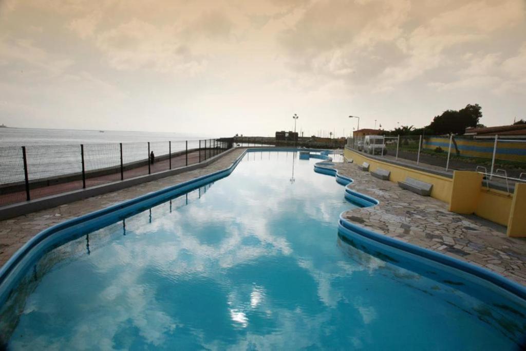 a pool of blue water next to the ocean at INATEL Oeiras in Oeiras