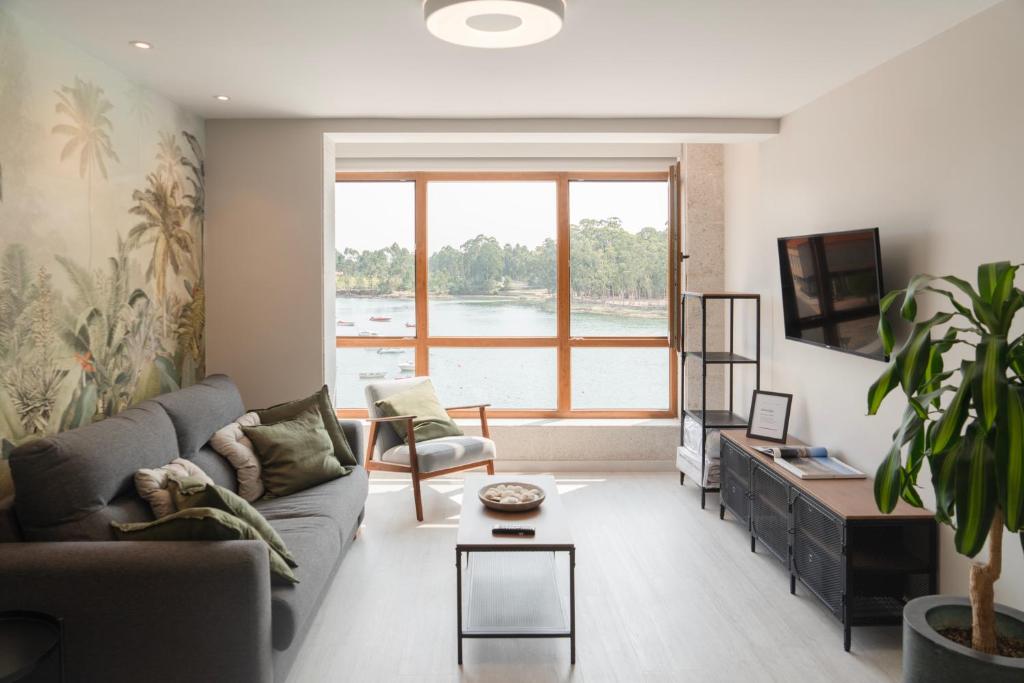 a living room with a couch and a large window at Apartamento Serea in Villanueva de Arosa
