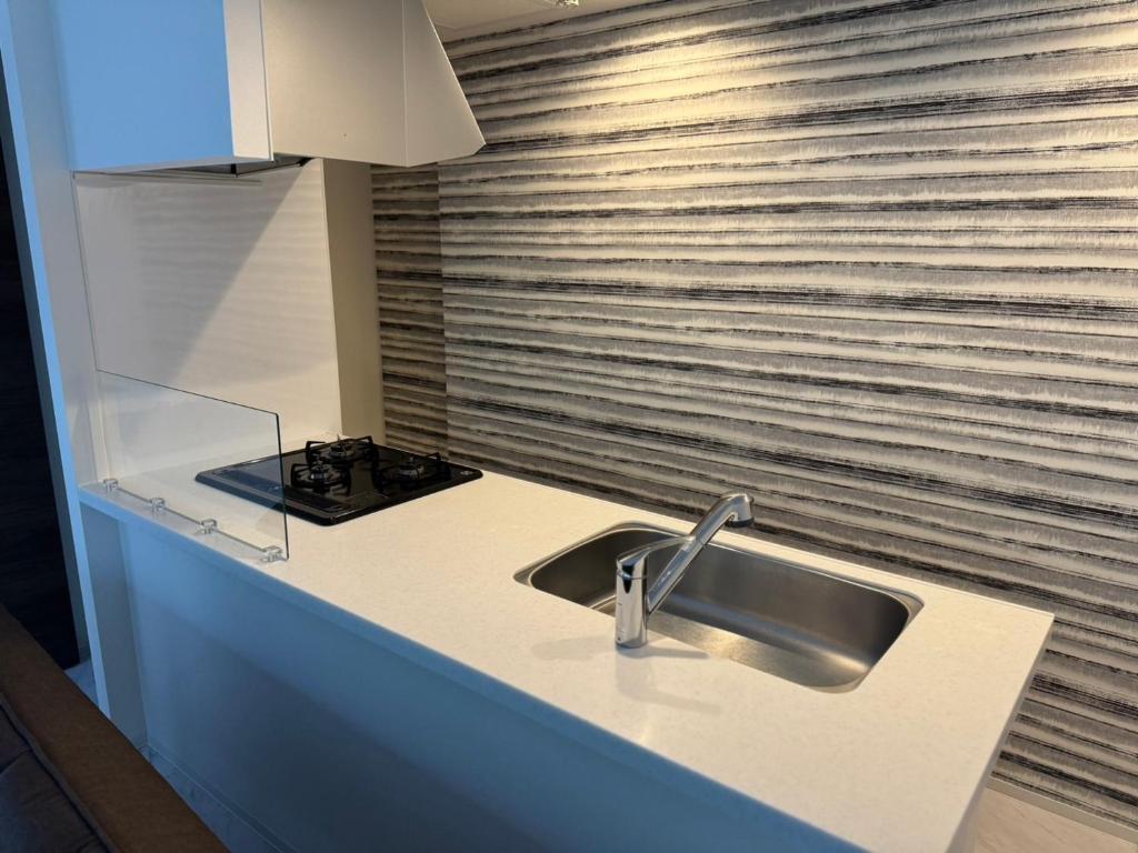 a kitchen counter with a sink and a stove at ホテル小樽キャナルビュー 海宝樓アネックス in Otaru