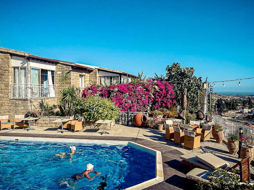 a couple of people swimming in a swimming pool at Cyprus Villages Hotel & Restaurant - Central Location - Bed & Breakfast - With Access To Pool And Stunning Views in Tochni