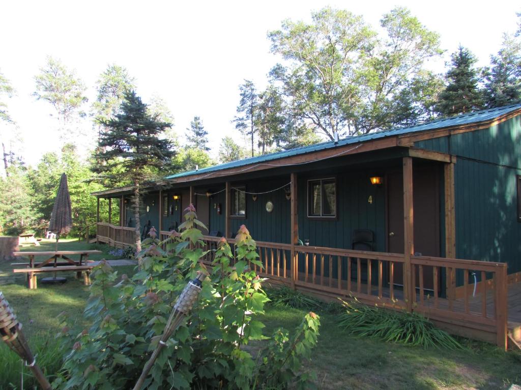 a green cabin with a porch and a picnic table at Best Bear Lodge in Irons