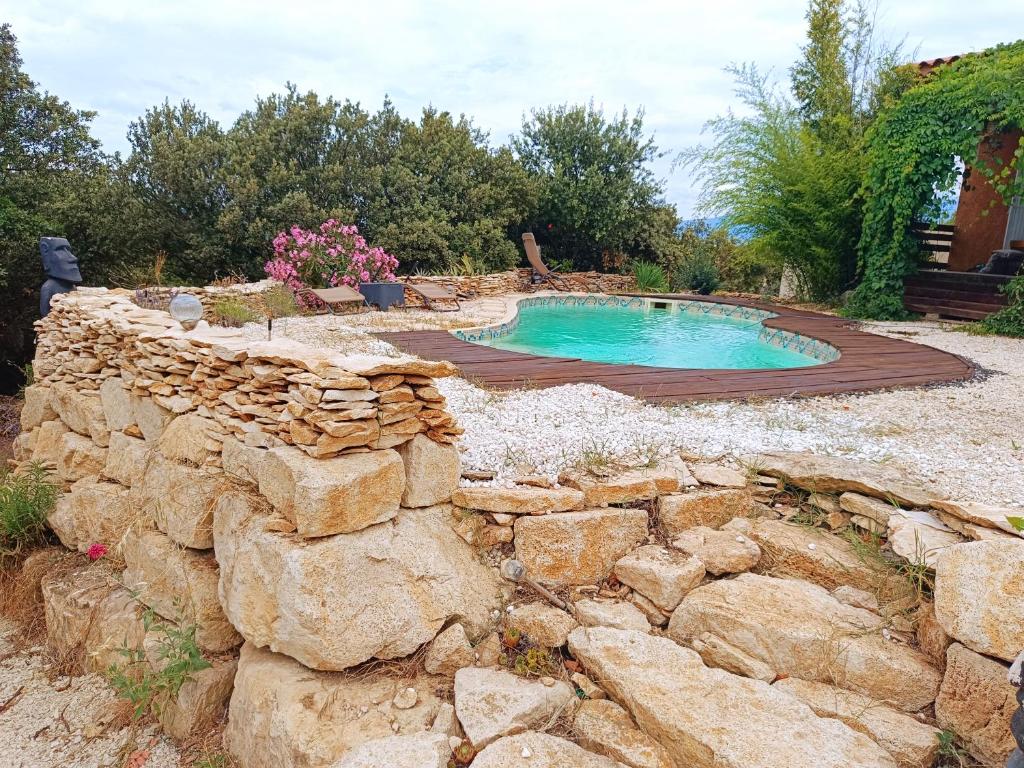 a stone retaining wall next to a swimming pool at Là où le Ciel est né Beau mas pierres et contemporain sur grande propriété vue Mont Ventoux dentelles de Montmirail in Blauvac