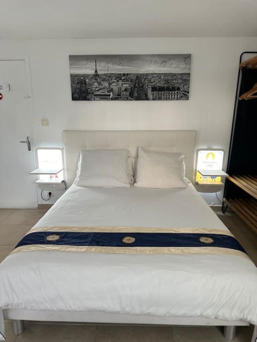 une chambre avec un grand lit blanc avec deux lampes dans l'établissement Studio proche de Centrex Paris Disney, à Noisy-le-Grand