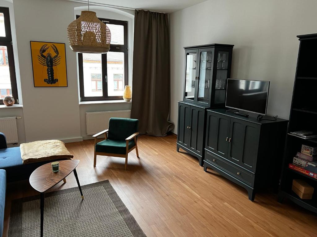 a living room with a tv and a chair at FeWo Luise mit 4-Zimmer, Balkon, 127qm in Görlitz