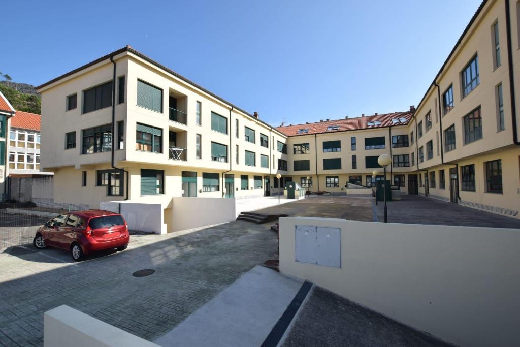 un'auto rossa parcheggiata in un parcheggio di fronte agli edifici di Apartamento Alfredo a O Pindo