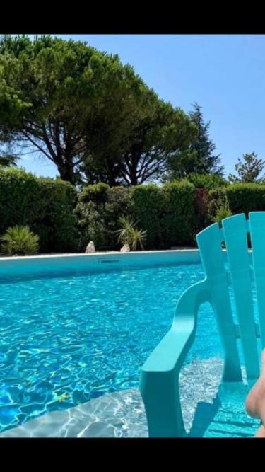 une chaise bleue assise à côté d'une piscine dans l'établissement Villa, à Sorgues
