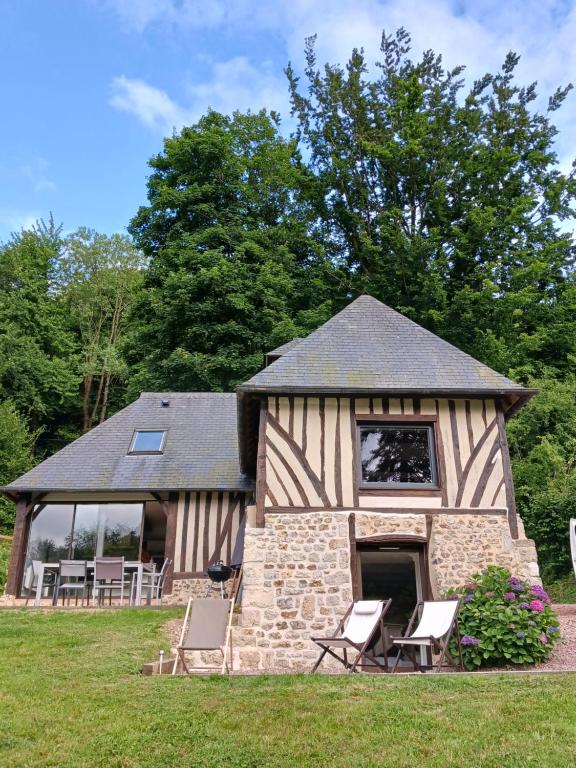 un bâtiment avec des chaises dans un champ avec des arbres dans l'établissement Gite La Vieille Rivière, à Genneville
