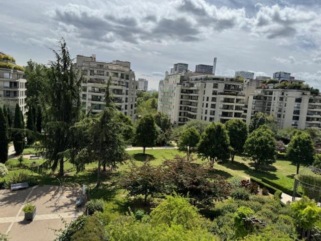 un parc avec des arbres et des bâtiments dans une ville dans l'établissement Paris Eiffel, à Paris