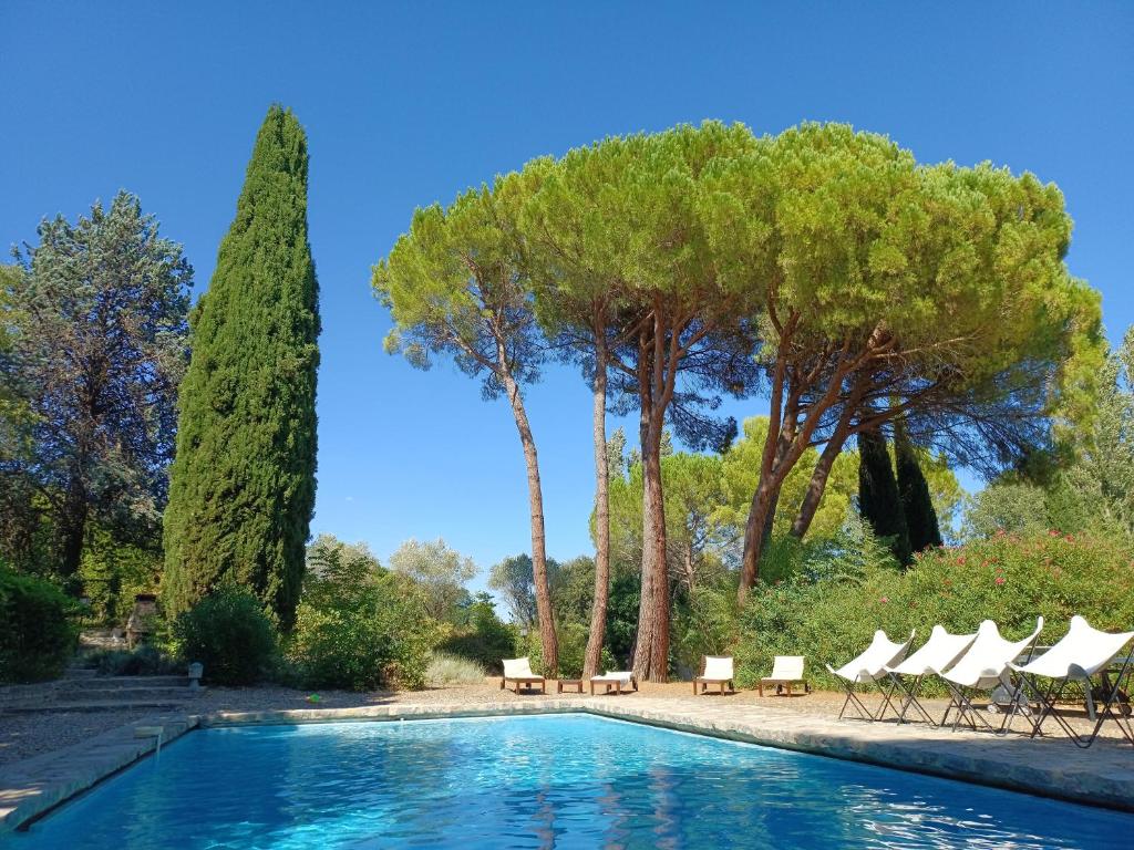 une piscine avec des chaises longues et des arbres dans l'établissement Le Mas de Rouvièges, à Le Pouget