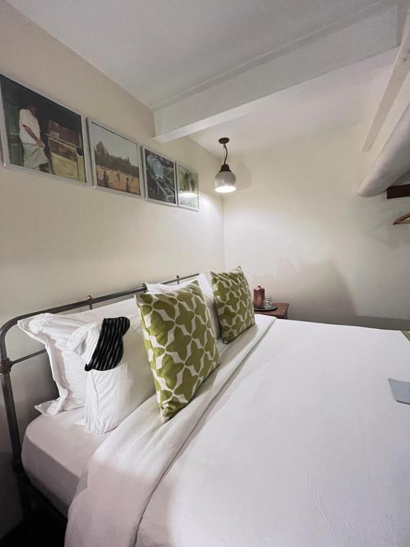 a bedroom with a white bed with green pillows at Abode Bombay in Mumbai
