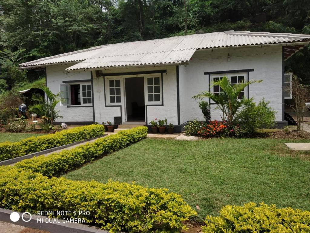 una piccola casa bianca con un cortile verde di Munnar heritage bungalow a Munnar