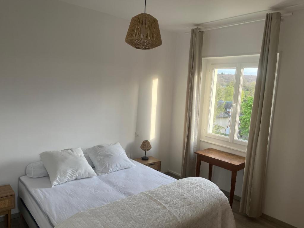 a bedroom with a white bed and a window at Aux Primevères in Saint-Honoré-les-Bains