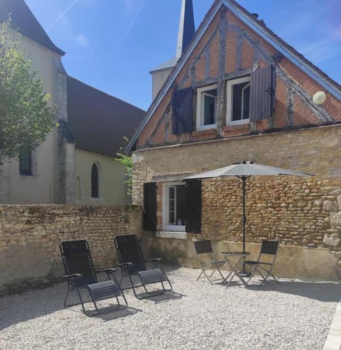 un groupe de chaises et un parasol devant un bâtiment dans l'établissement Séjour champêtre et bucolique, à Saint-Maurice-sur-Fessard
