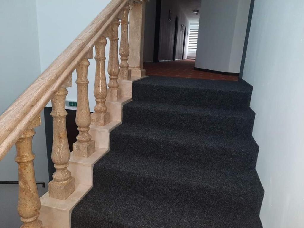 a stairway with black carpet and wooden stairs at Surianu Events Hotel-Restaurant in Orăştie
