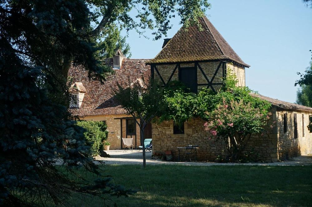 un grand bâtiment en briques avec une fenêtre et une chaise dans l'établissement le Bosc de castang, à Pressignac