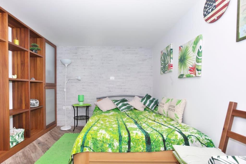 a bedroom with a bed with a green comforter at Green cottage Baredi, Izola, Slovenia in Izola