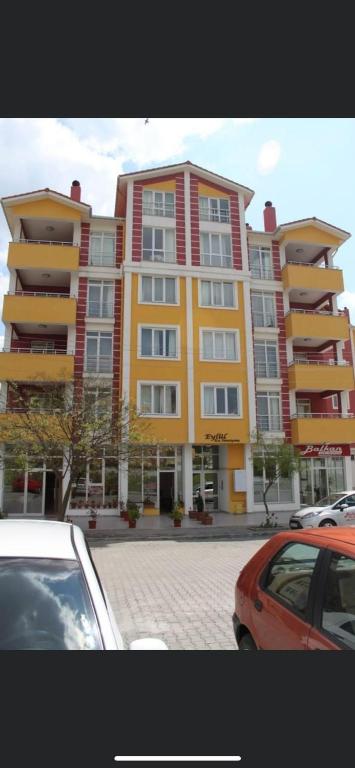 a large building with cars parked in a parking lot at EDİRNE EYLÜL PANSİYOn in Edirne