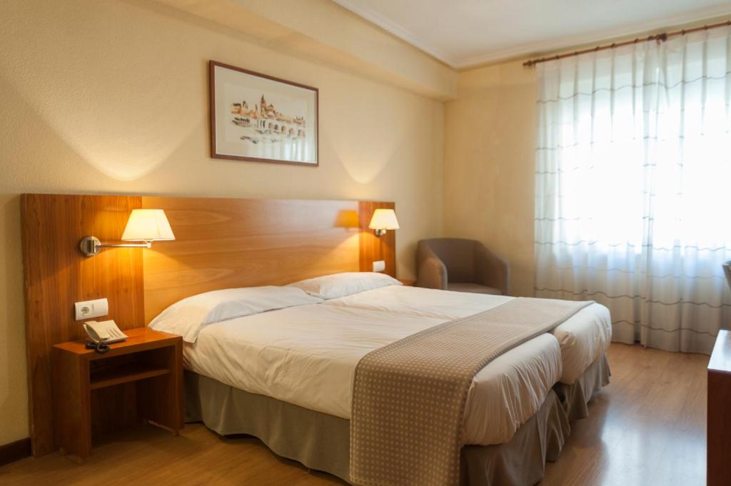 um quarto de hotel com uma cama grande e uma janela em Hotel Mercado by gaiarooms em Salamanca