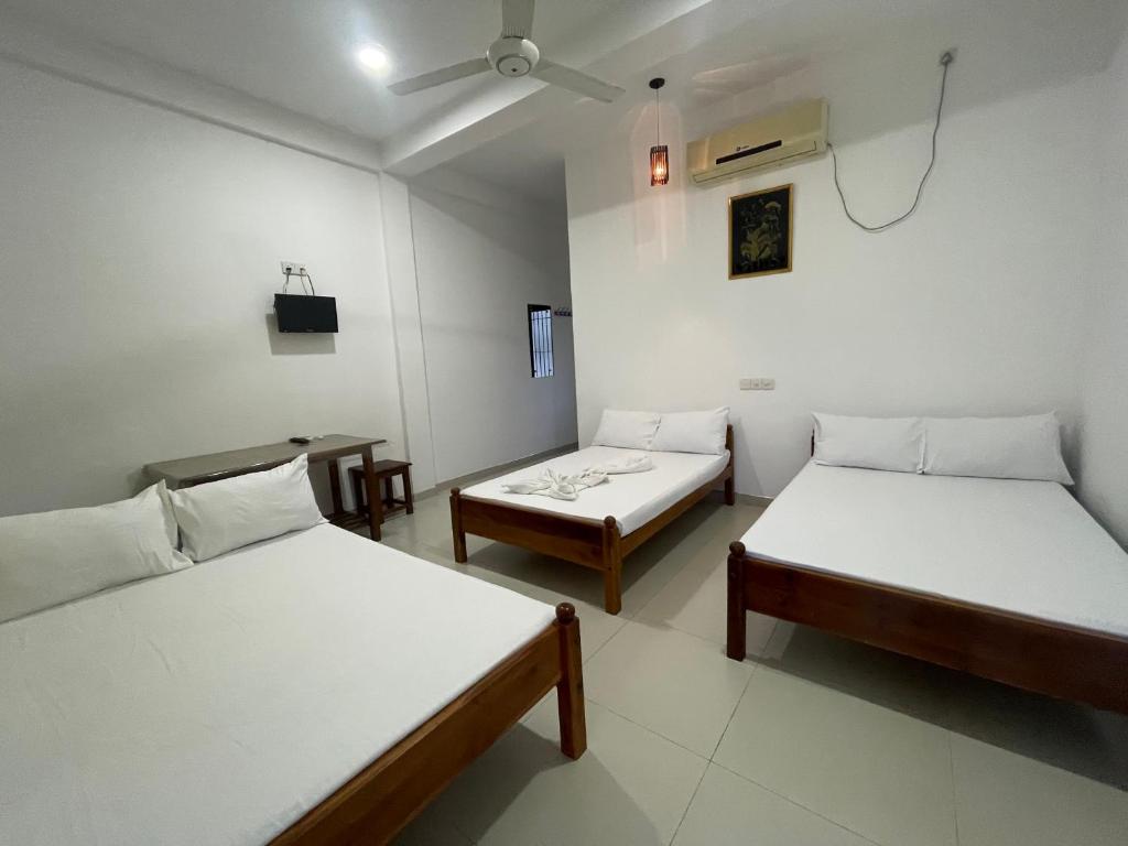 a room with two beds and a tv in it at Rathna Holiday Resort in Kataragama