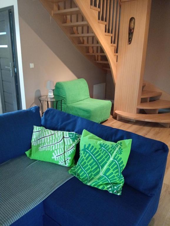 a blue couch with green pillows and a green chair at Apartamenty Dzika Orlica in Zieleniec