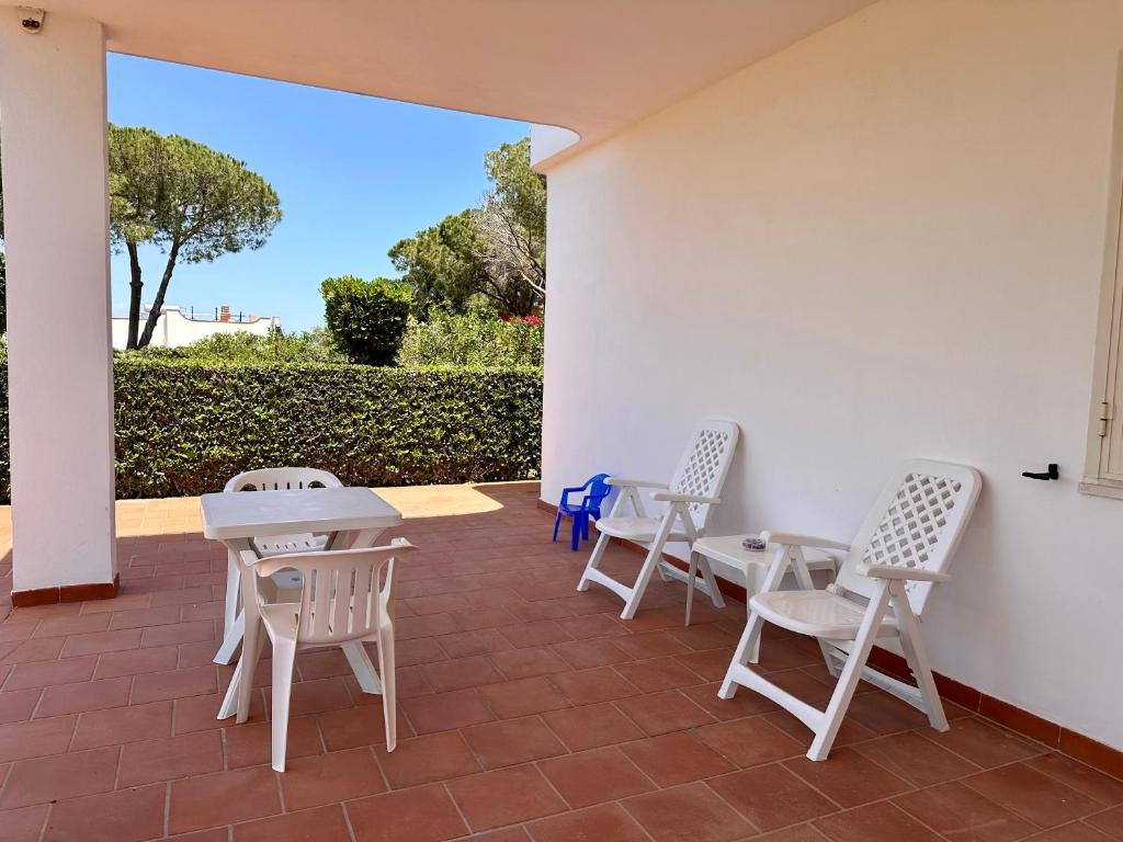a patio with white chairs and tables and a wall at L'isola di Gianni by Ortigia Apartments in Plemmirio