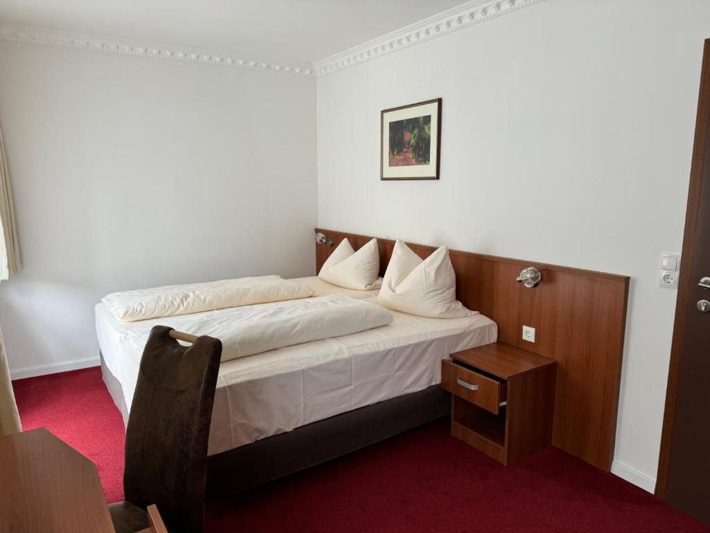 a small bedroom with a bed with white sheets at Hotel zu den Burgen in Kamp-Bornhofen