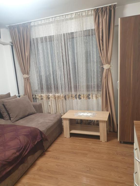 een slaapkamer met een bed en een tafel voor een raam bij Închiriez garsoniera in Regim Hotelier Berceni-Sun Plaza in Boekarest