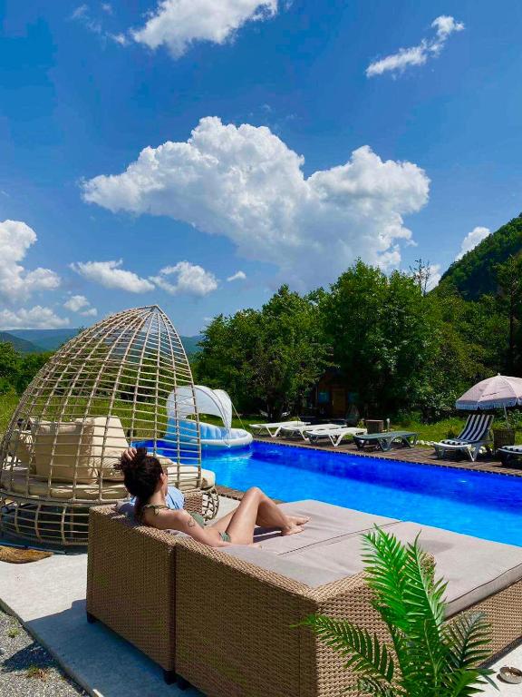 a woman sitting on a bed next to a swimming pool at Garemo in Ambrolauri