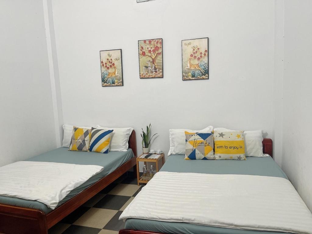 two beds in a room with paintings on the wall at Hiệp Đạt Motel in Kon Tum