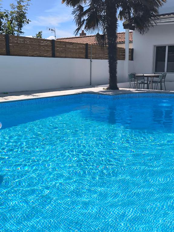 une piscine bleue avec une table et un palmier dans l'établissement Appart'cosy - 7 personnes, à Saint-ouen-dʼAunis
