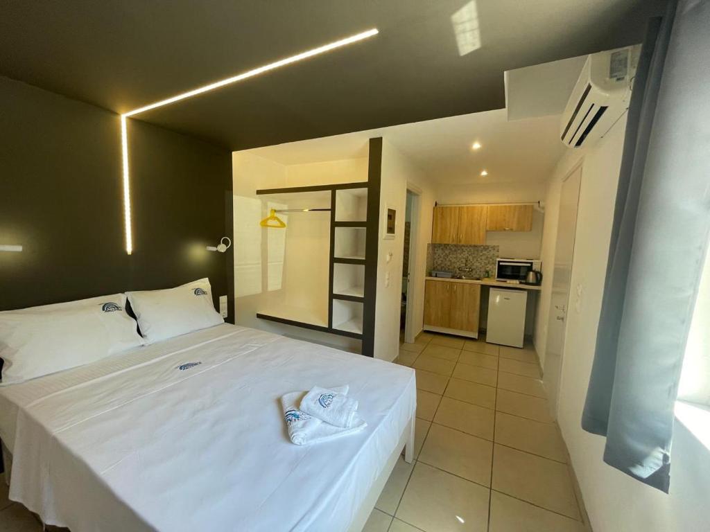 1 dormitorio con 1 cama blanca grande y cocina en Hotel Benitses Arches, en Benitses