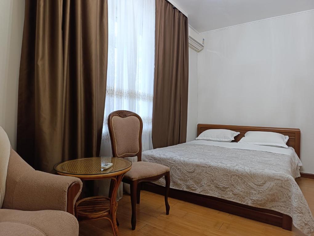 een slaapkamer met een bed, een stoel en een tafel bij AURA on Tynystanova street 199 in Bisjkek