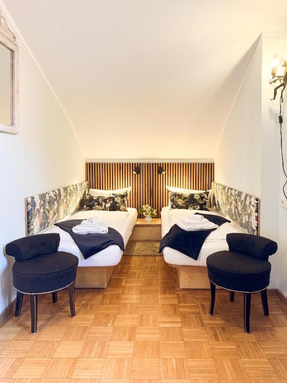 two beds in a room with two chairs at Villa Fantasia Budget Boutique Hotel in Füssen