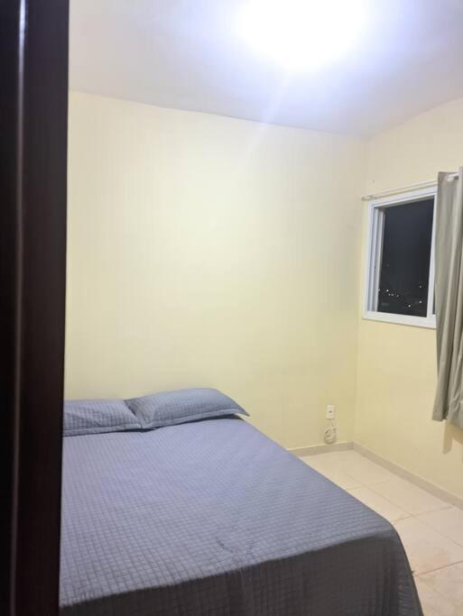 a bedroom with a bed with blue sheets and a window at Quarto de Casal Bem Localizado Em apto Compartilhado AP 204 in Uberaba