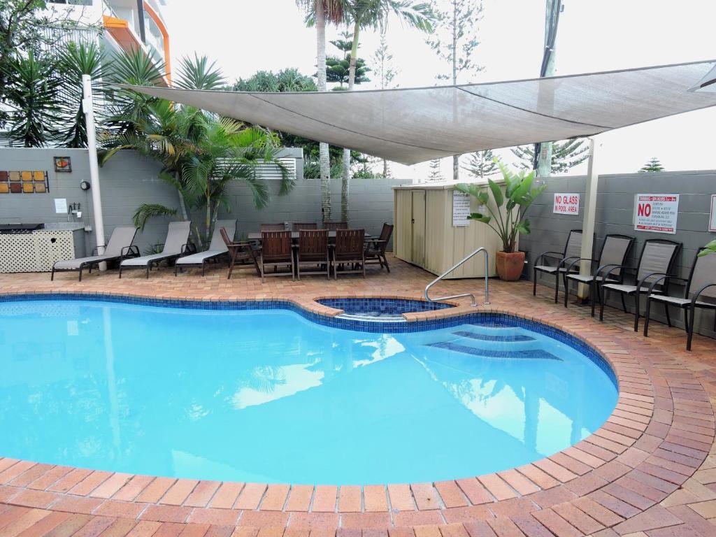 Una gran piscina azul con sillas y una mesa. en Bayview Beach Holiday Apartments, en Gold Coast