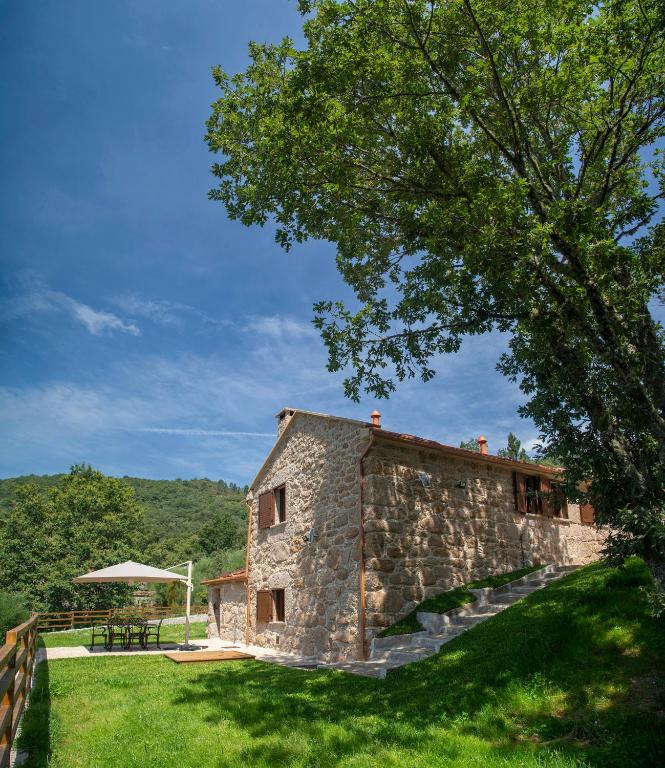 a stone house with a picnic table and a tree at Casa do Fasco in Castro Laboreiro
