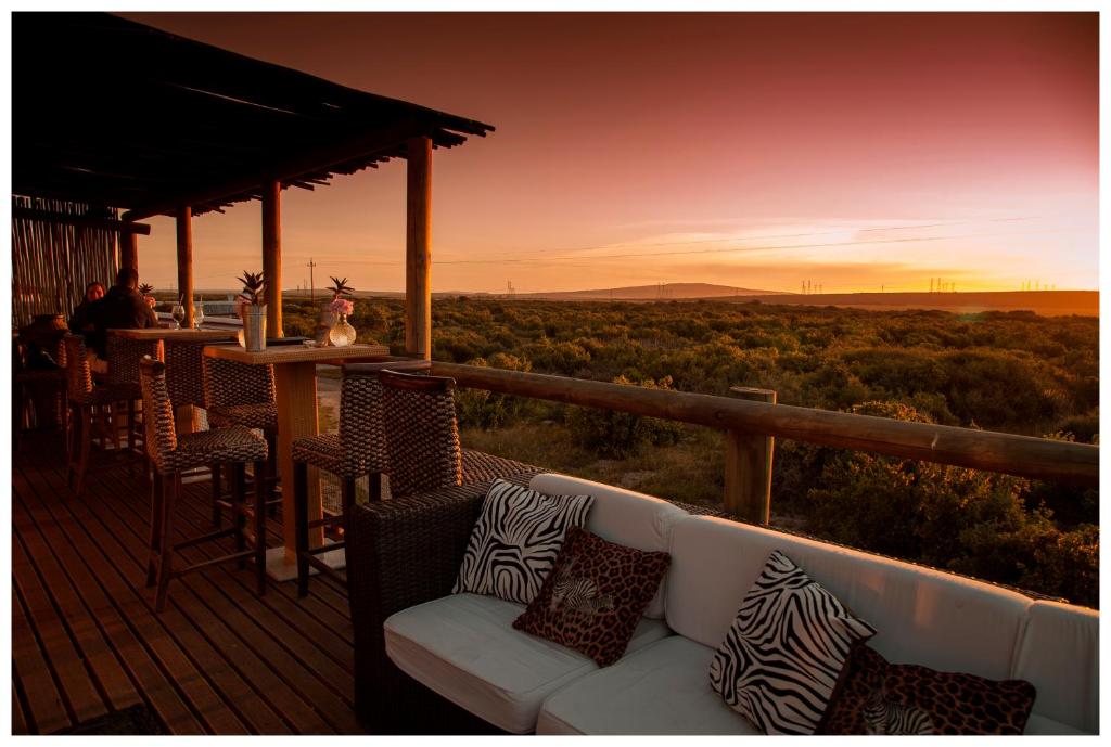 a couch on a deck with a view of the desert at Thali Thali Game Lodge in Langebaan