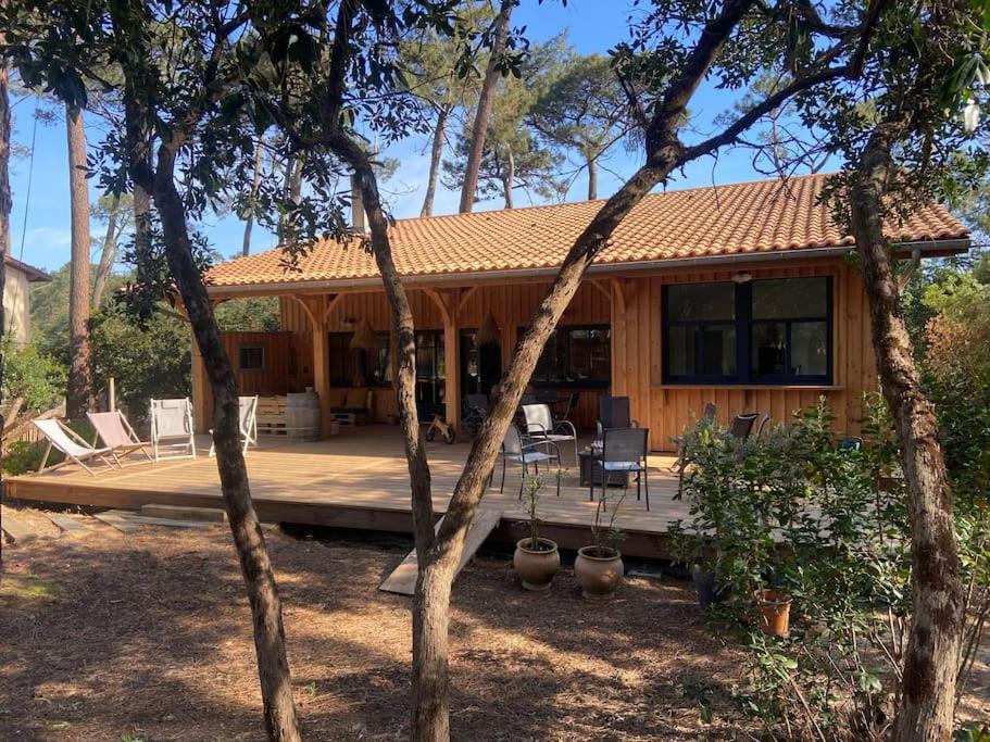 une maison dotée d'une terrasse avec des chaises et des arbres dans l'établissement Grande maison idéale pour familles, à Lège-Cap-Ferret